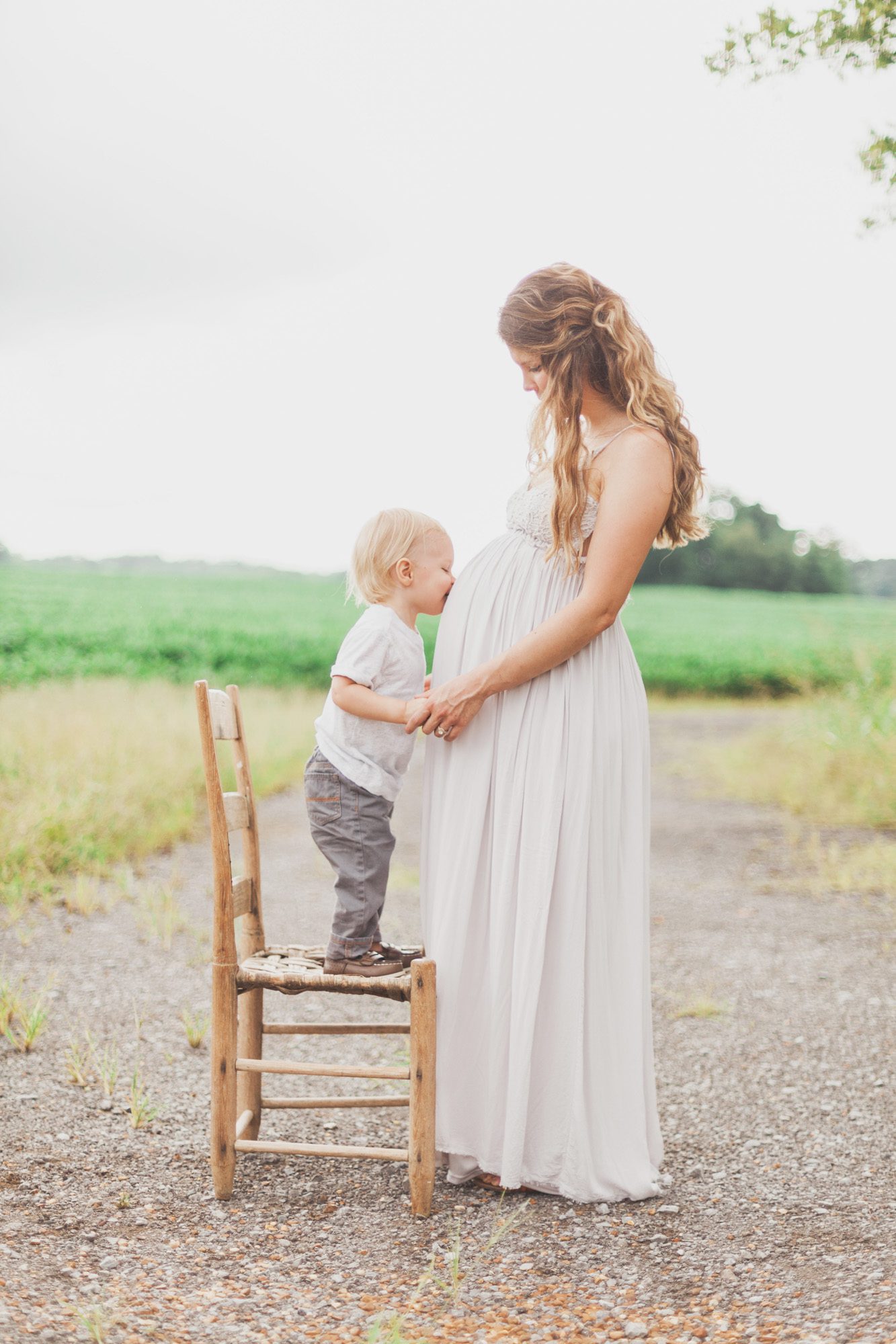 Maternity photos with family at farm, mom with son kissing bump