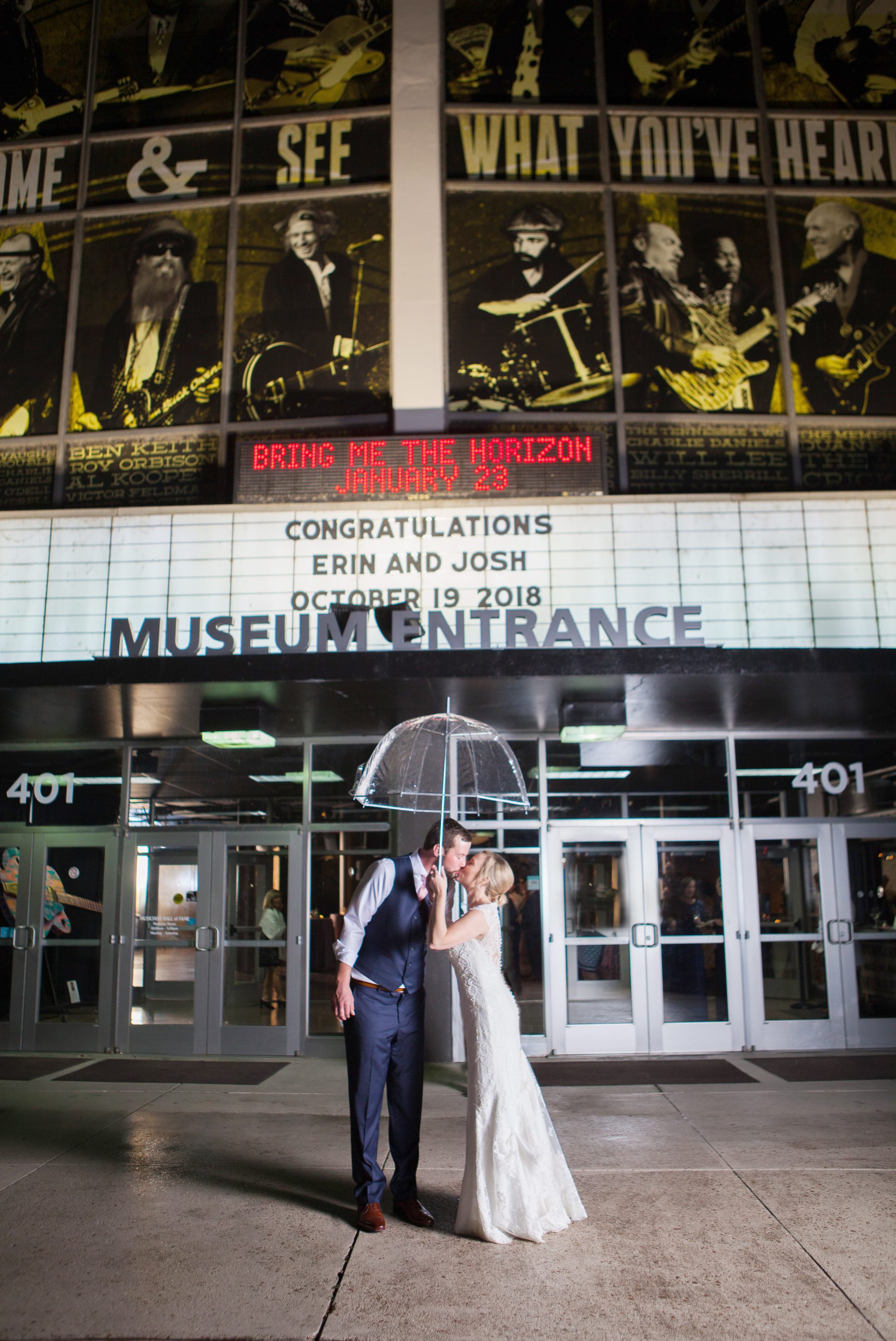 Bride and groom pose for photo in light rain in front of marquee after wedding photography at Musicians Hall of Fame in Nashville TN photos by Krista Lee 