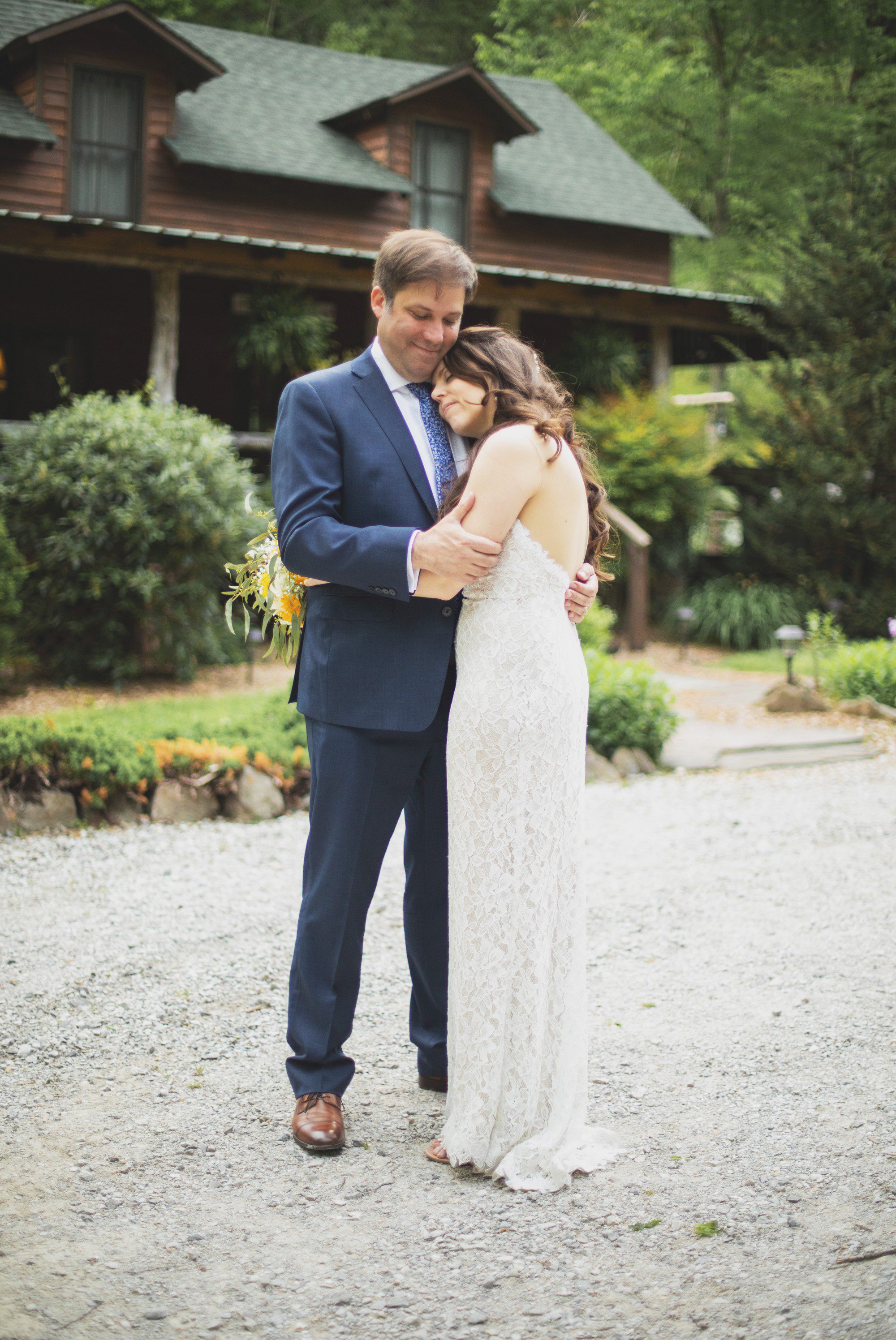 Bride leans on groom's chest in front of cabin after elopement wedding ceremony at Butterfly Hollow in Gordonsville, TN. Photos by Krista Lee Photography. 