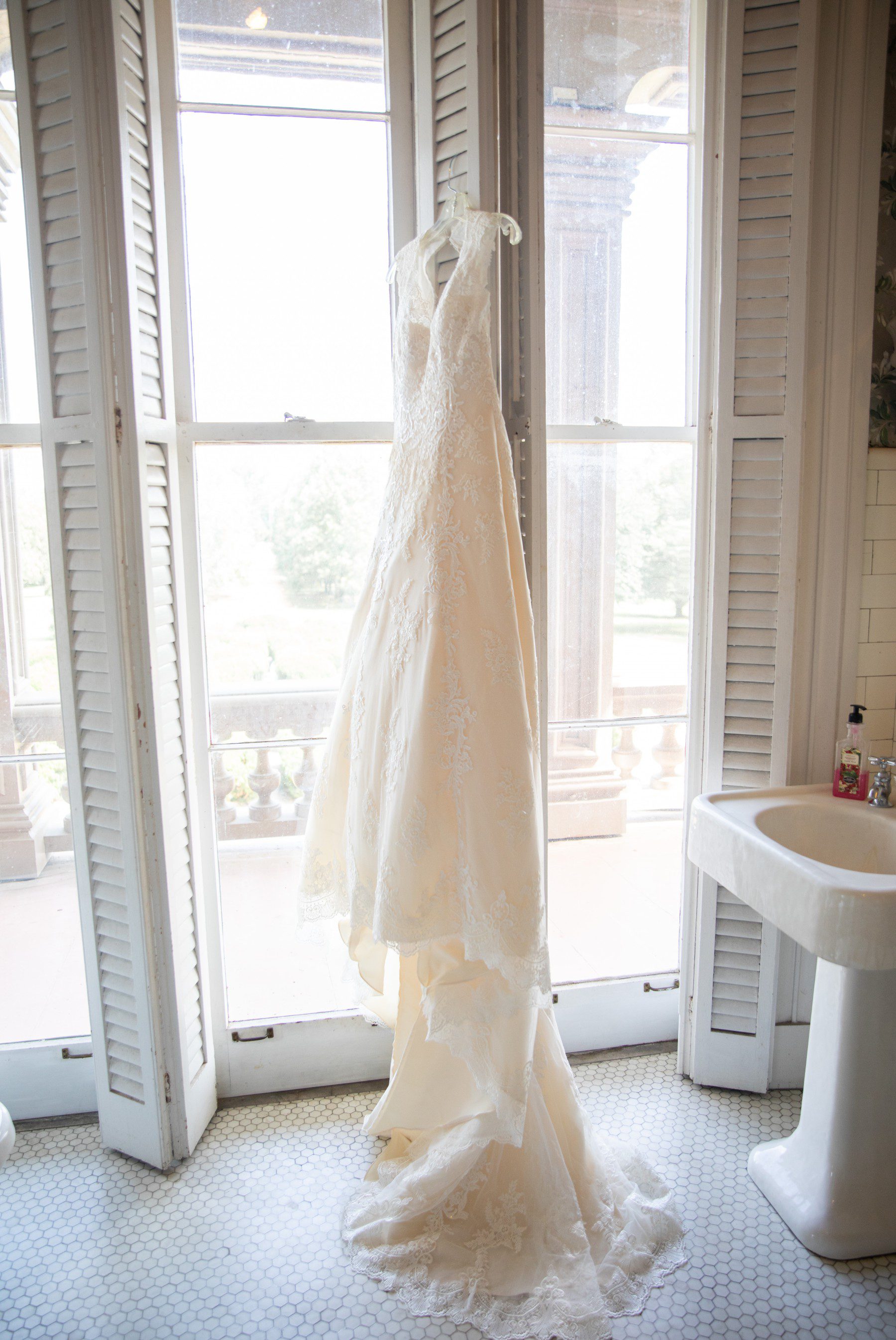 Brides dress hangs in the window before the wedding ceremony at Two Rivers Mansion Nashville