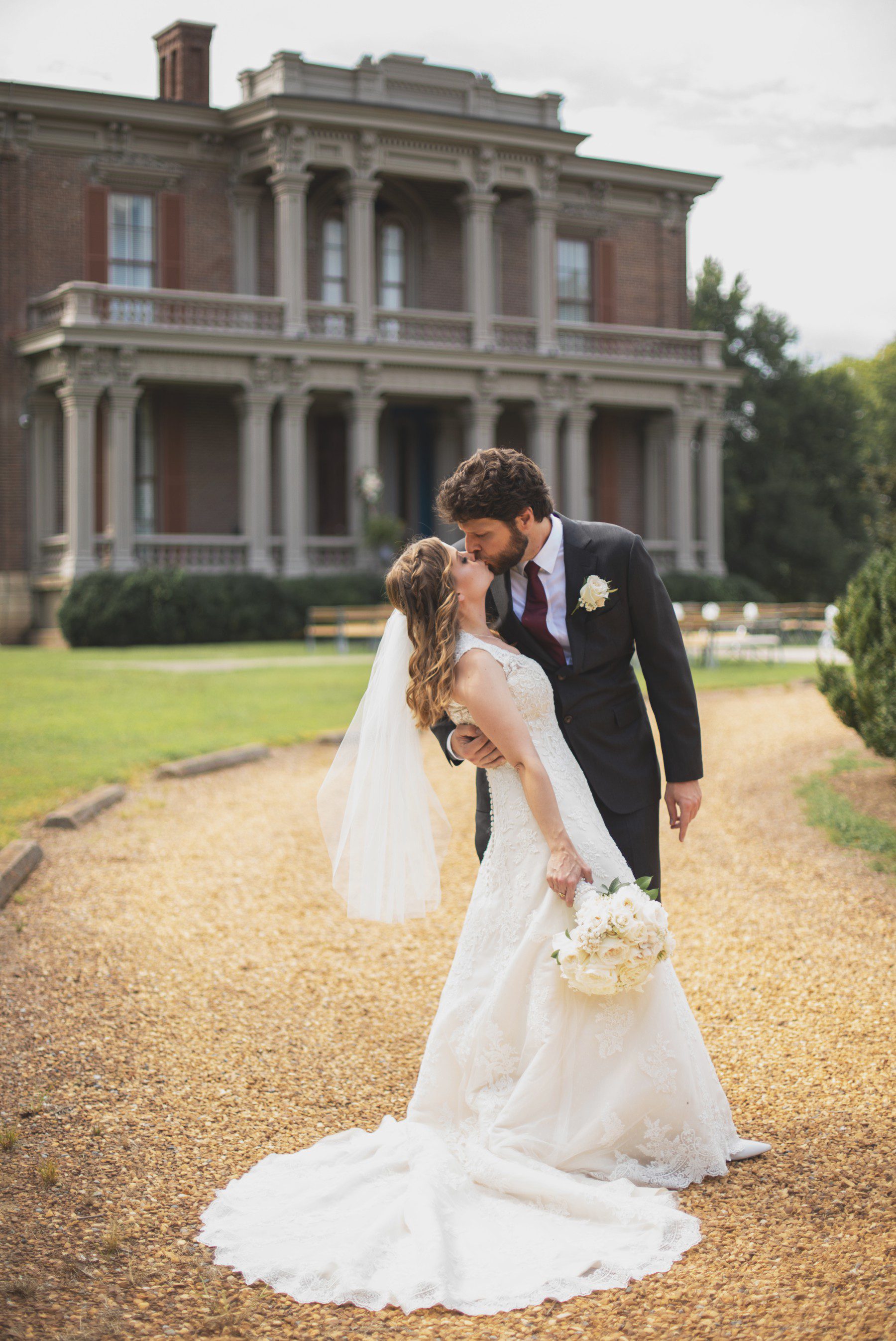 Bride and groom kiss in front of Two Rivers Mansion