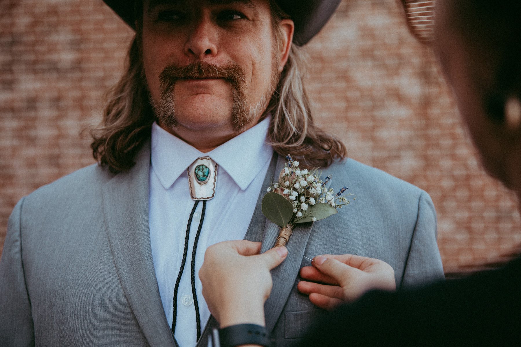 country groom getting boutonniere pinned 