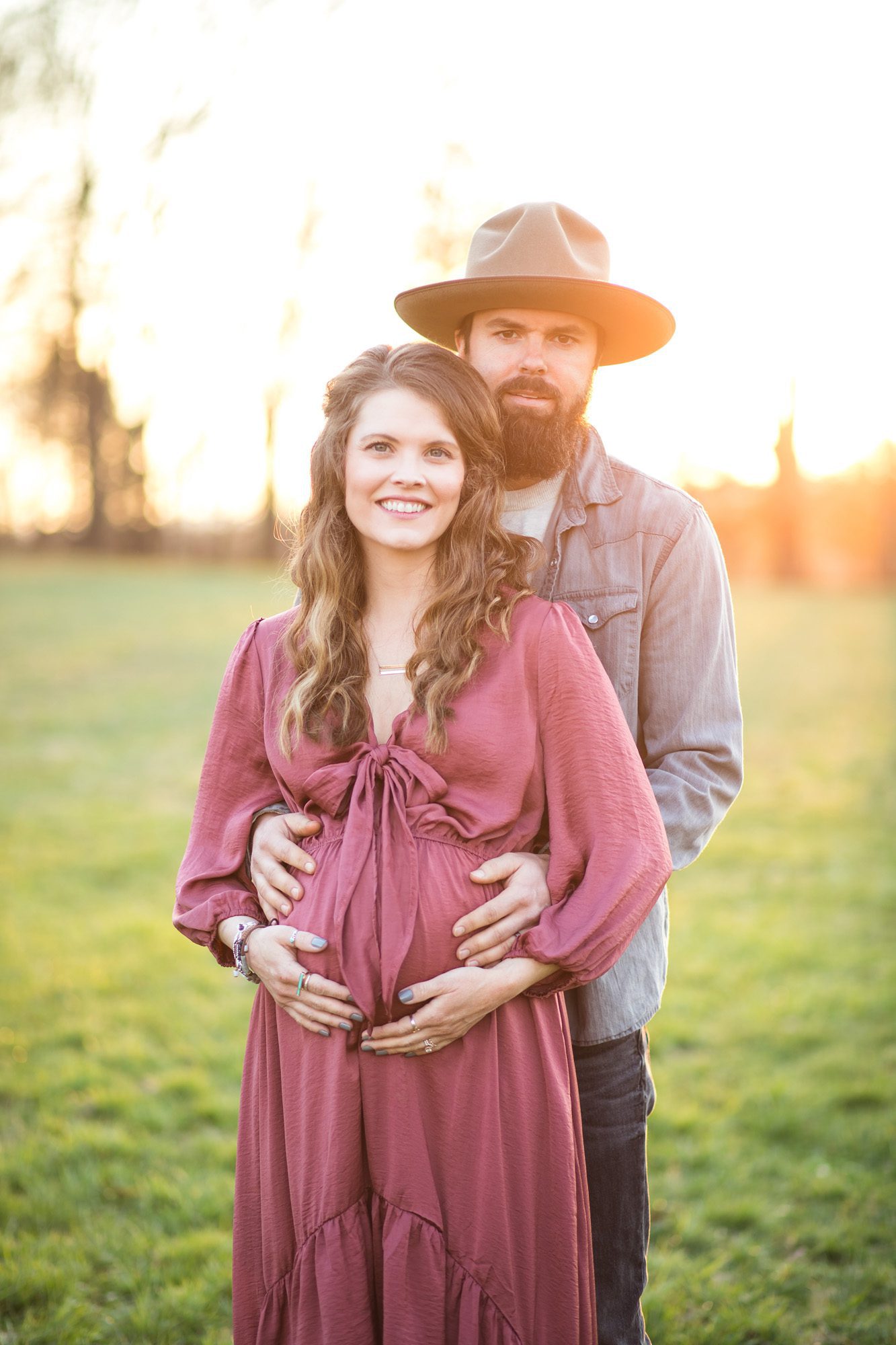 Pretty couple photo maternity session in a field at sunset 