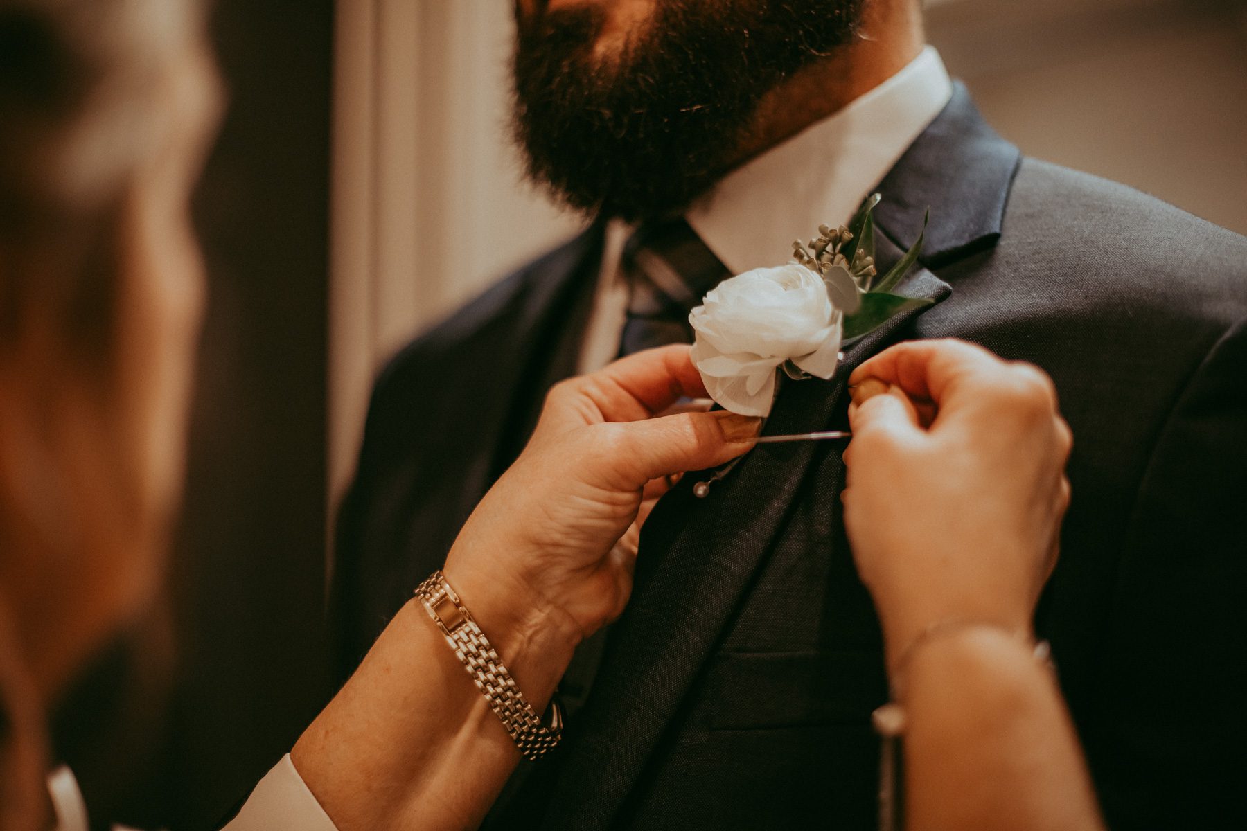 Groom getting his boutonniere pinned on wedding day 