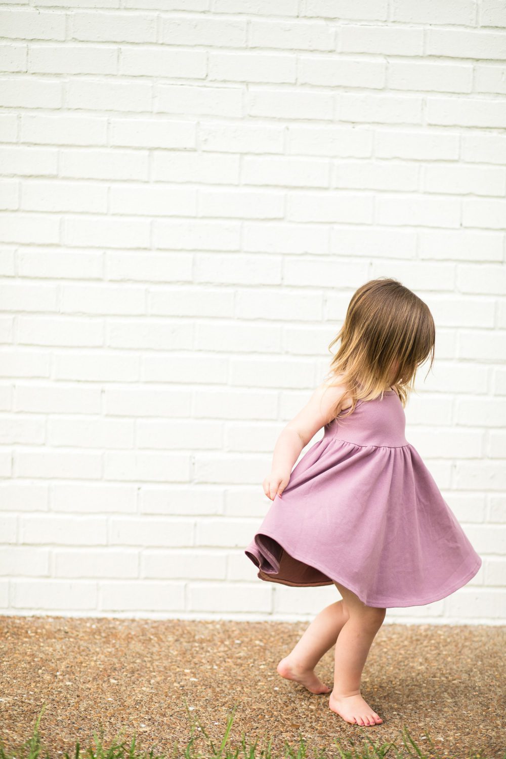 Sweet little girl on white brick wall bare feet 