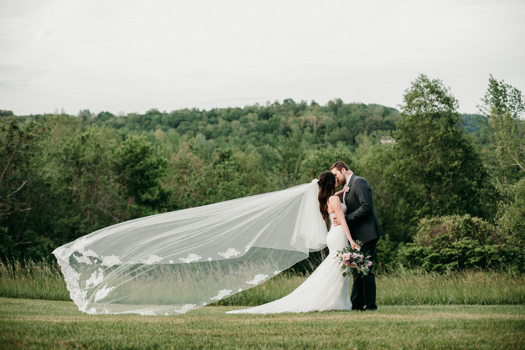 Romantic outdoor portrait with bride and groom and flowing veil 